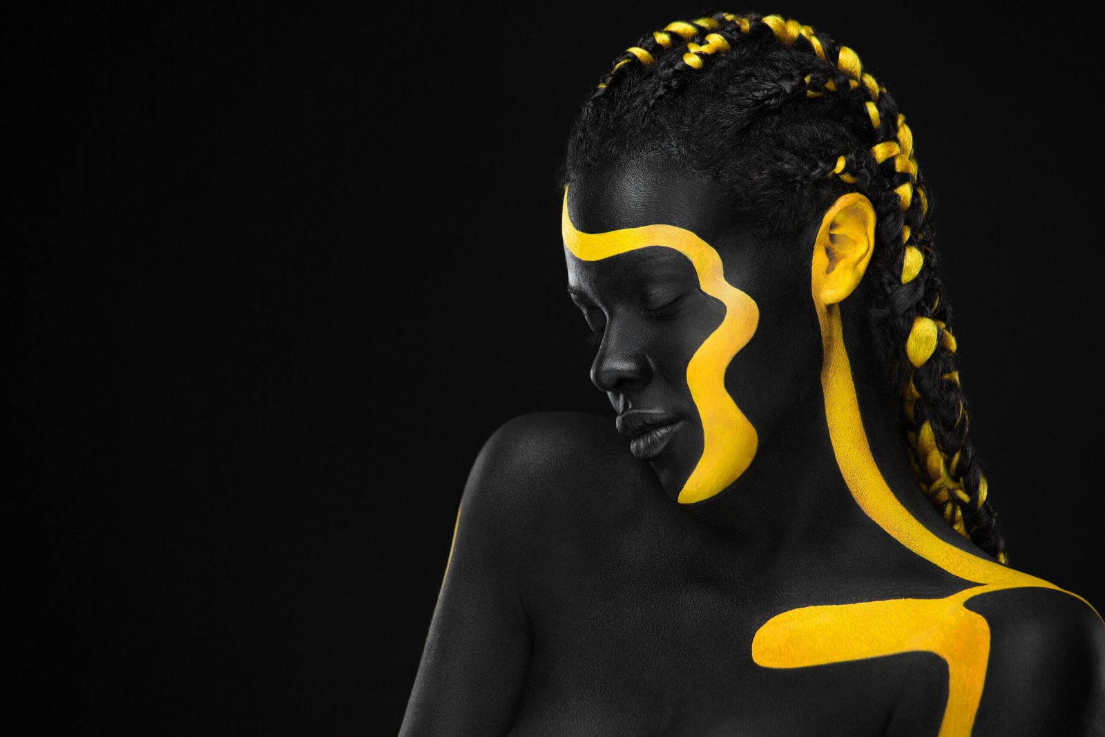Yellow and black body paint. Woman with face art. Young girl with bodypaint. An amazing model with makeup.